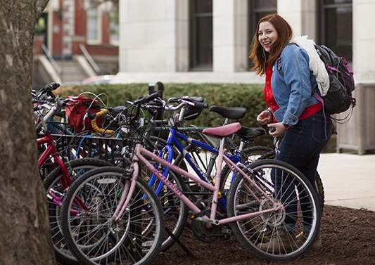A student gets her bike from the bike rack outside of George Davis Hall. 