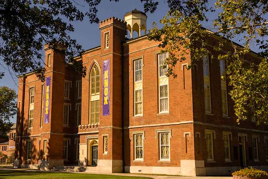 South side of Old Main in the sun light. You can see both purple Knox banners hanging on each column. 