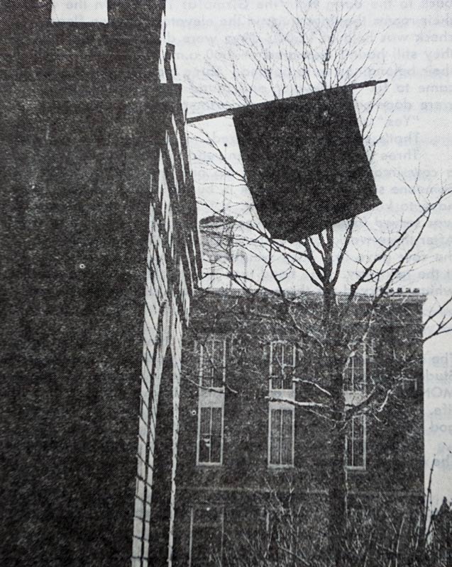Photo of black flag on the brick tower. 