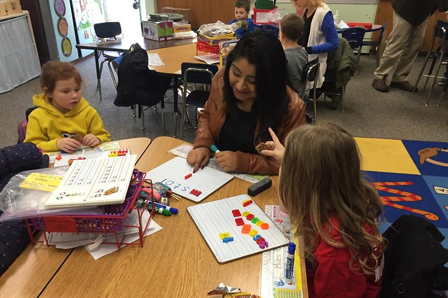 Karina Martinez, Knox College student volunteer, works with Galesburg, kindergarten students in this Grants in Place-funded early literacy program. 