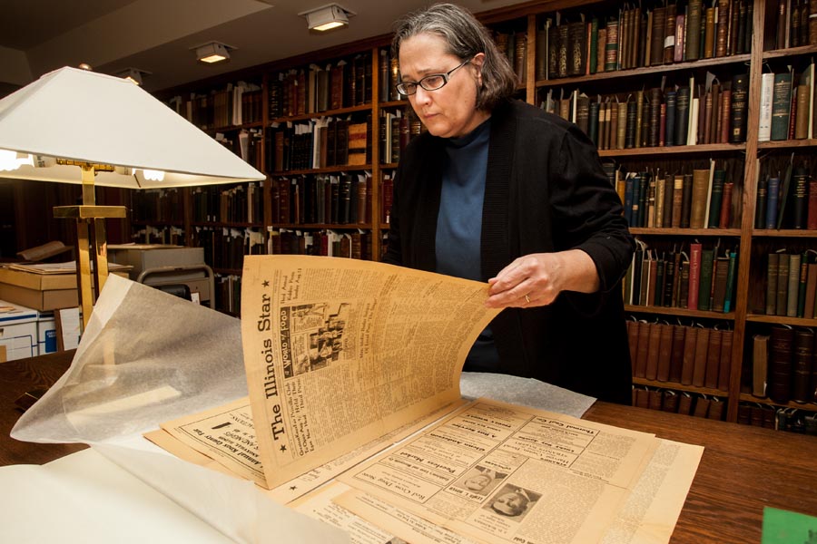 Knox College library staff Laurie Sauer examines issues of The Illinois Star, a black community newspaper in Galesburg in the mid 20th century.