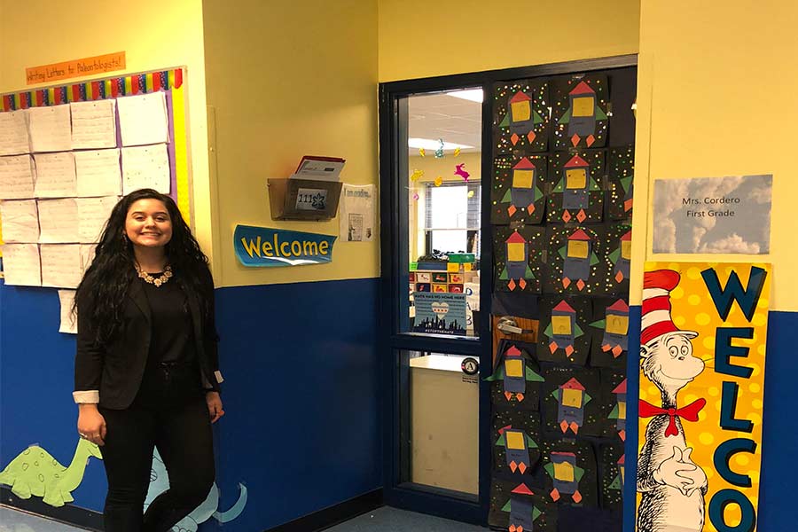 Stephanie Cordero '17 in front of her first grade classroom.
