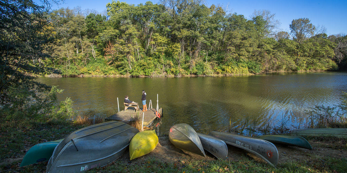 Canoes sit on the shore of a lake at the Green Oaks Biological Field Station. 