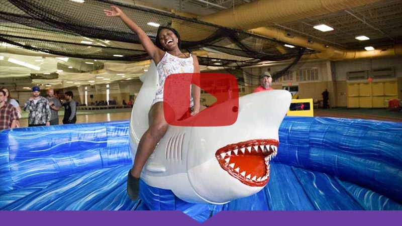 A Knox College student enjoys Flunk Day on a mechanical shark