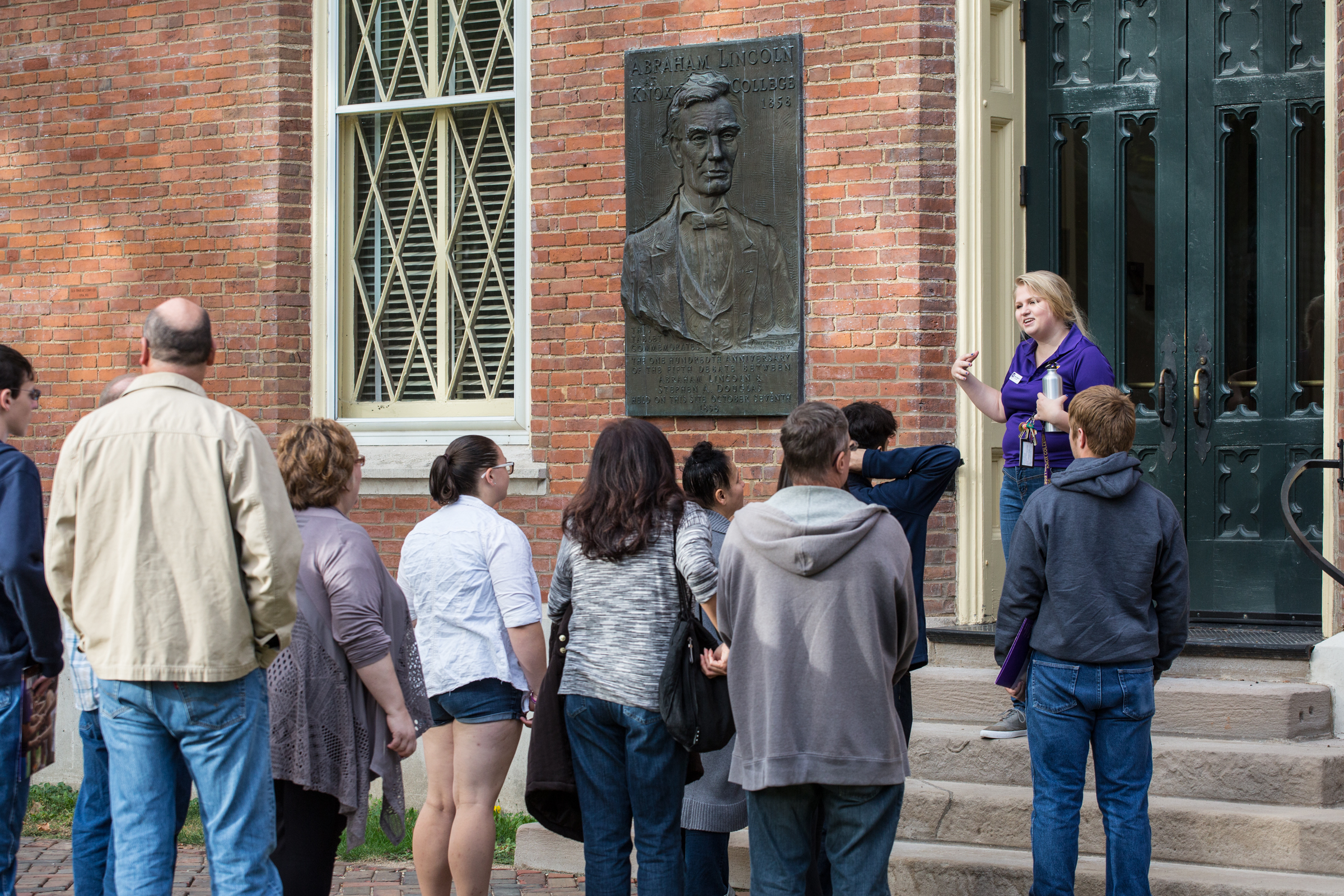 A tour guide is giving a tour to prospective students outside of Old Main.