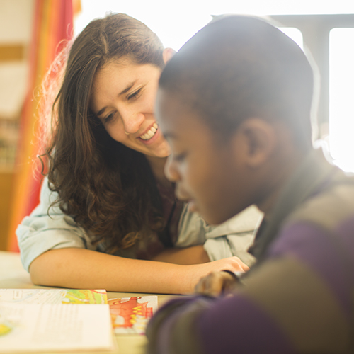 A student helps an elementary student read a book during Reading Buddies. 