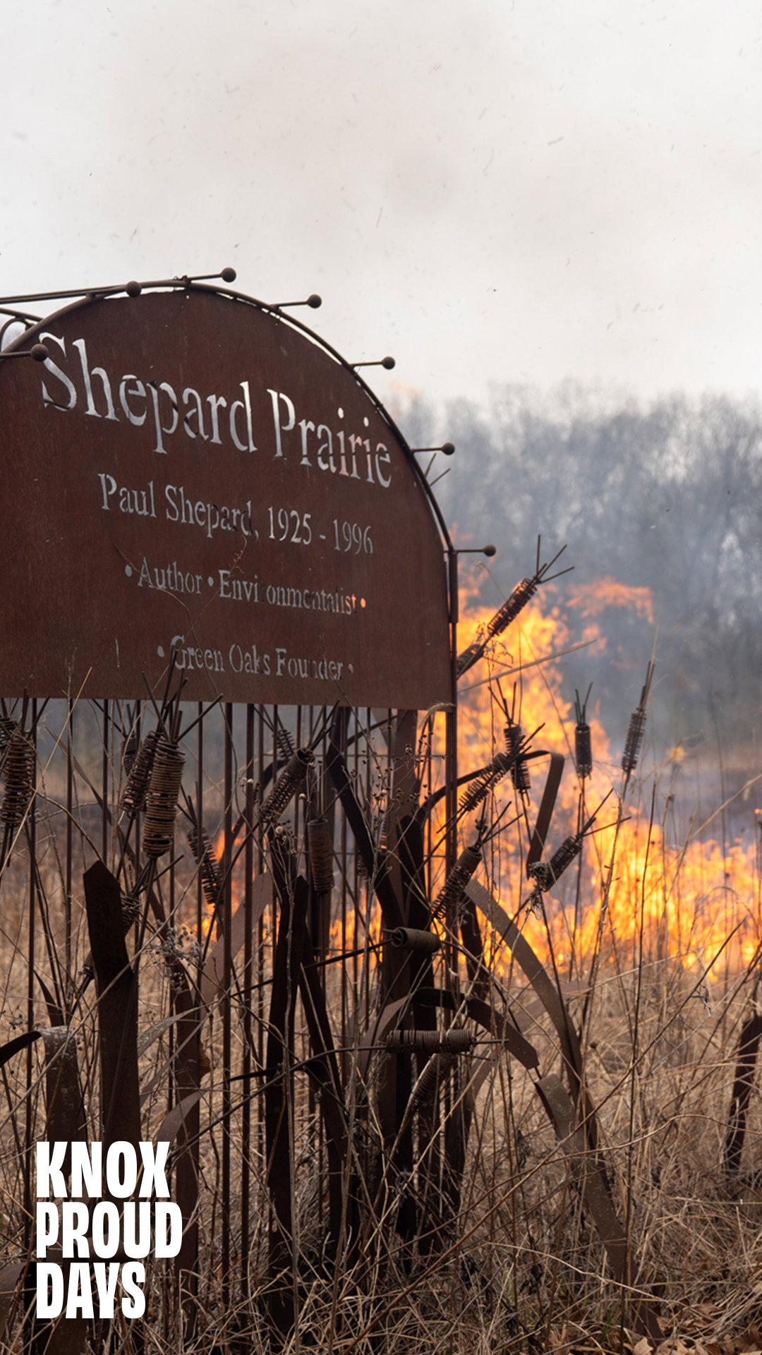 A sign sitting in a prairie reads Shepard Prairie. There is a fire in the background on the prairie. Knox Proud Days is in the bottom left.