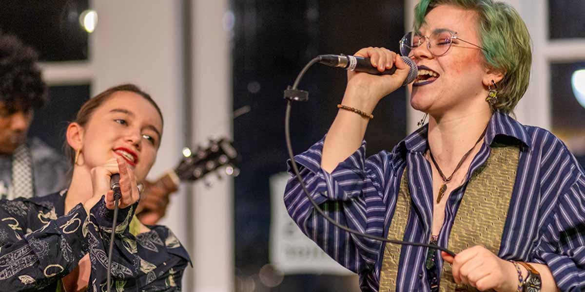 Two students singing and playing instruments during the Knox Rocks concert.