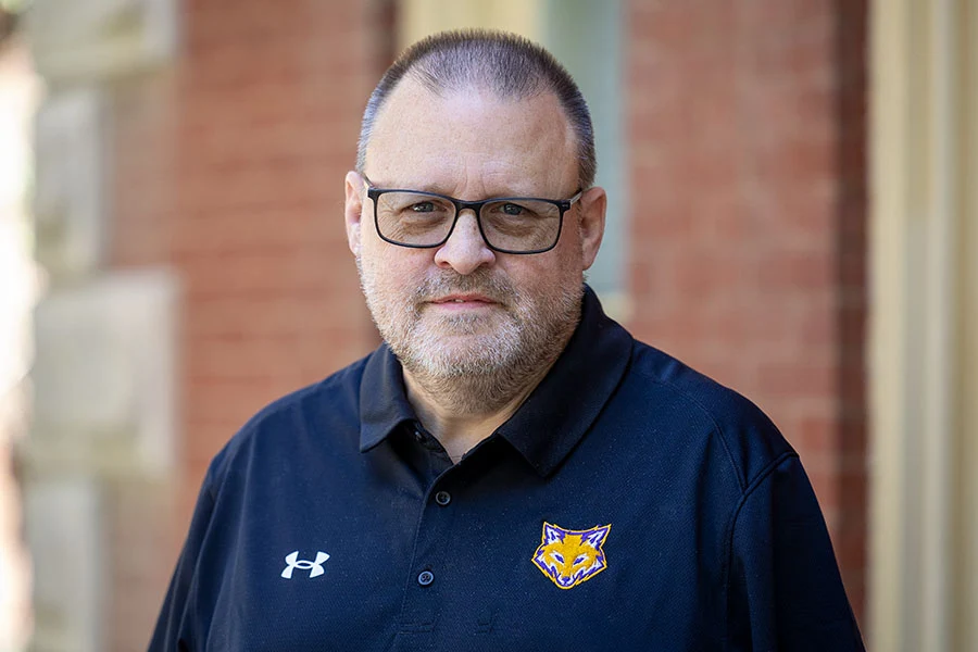 Chris Dickson headshot. He wears a polo with the Knox mascot logo—a fox head—embroidered.