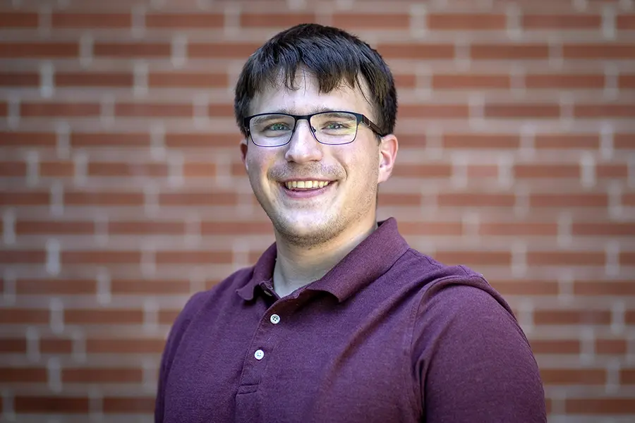 Justin Seiberlich smiles, a brick wall behind him.