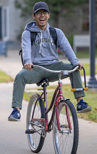 A student enjoys his ride across campus on his bicycle. 