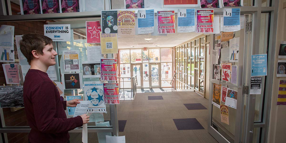 Students places a poster at Knox College