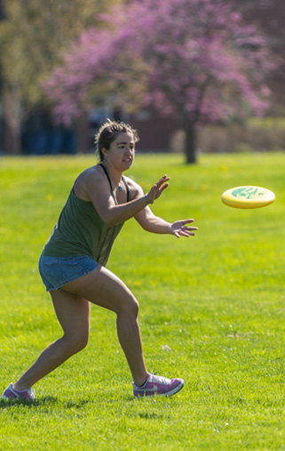 Student playing frisbee on the lawn