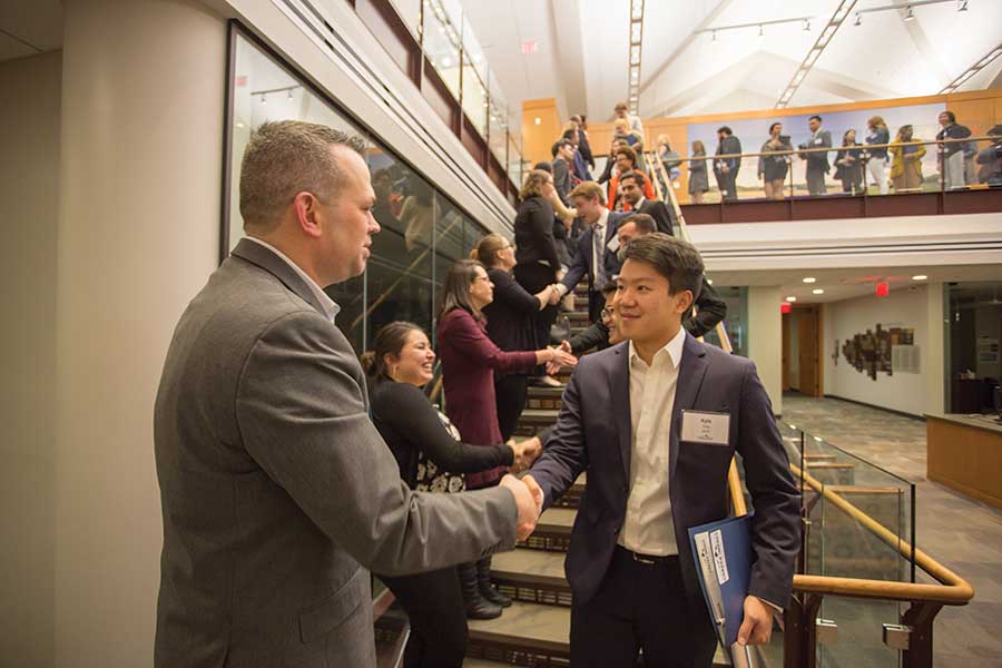 Kyle Yang '19, an integrative business and management major, greets alumni presenters at Knox's sixth annual Career Impact Summit.