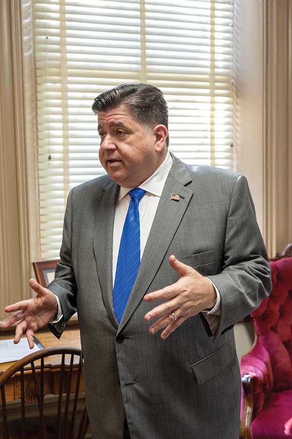 Governor Pritzker standing in a room talking.