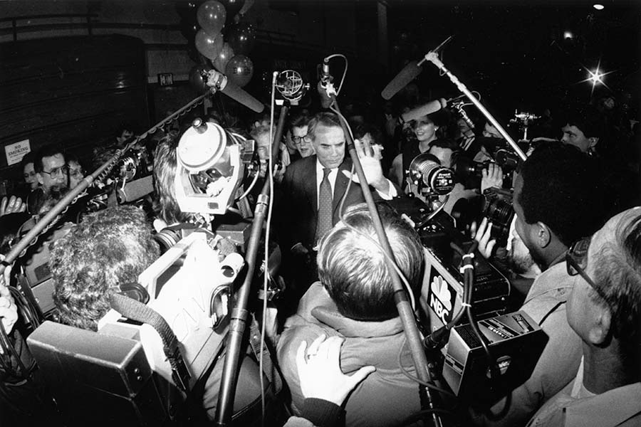 a black and white photo of a politician with photographers around him.