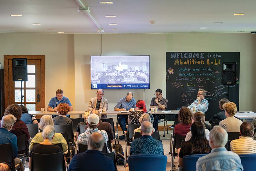 An audience sits in chairs in the Abolition Lab while a panel sits at the front of the room at a table.