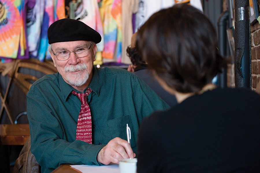 Donald Revell holds a pen in his hand as he speaks with a student.