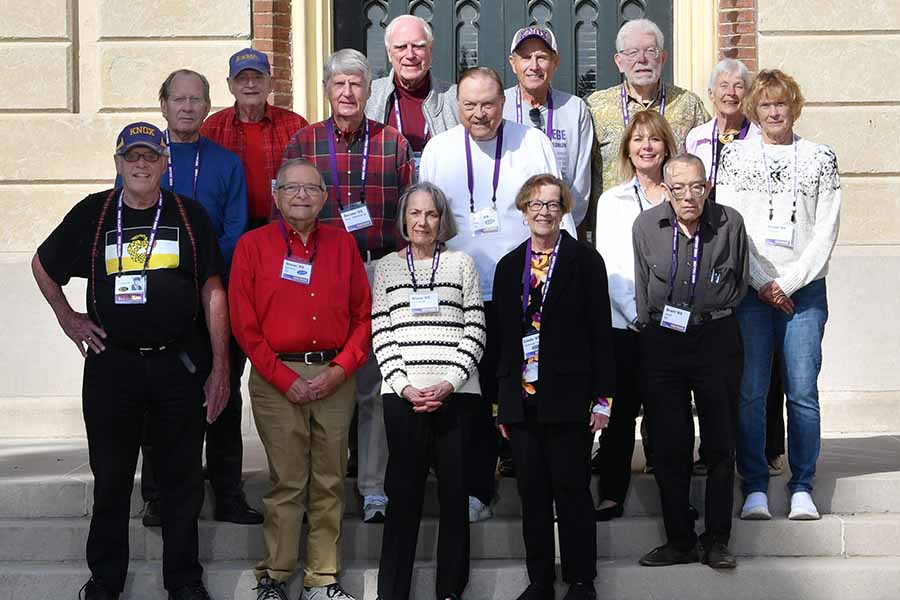 The Class of 1965 stands outside old main and poses for a photo.