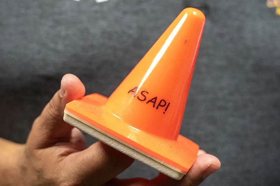 A small orange construction cone with "ASAP!" printed on it.