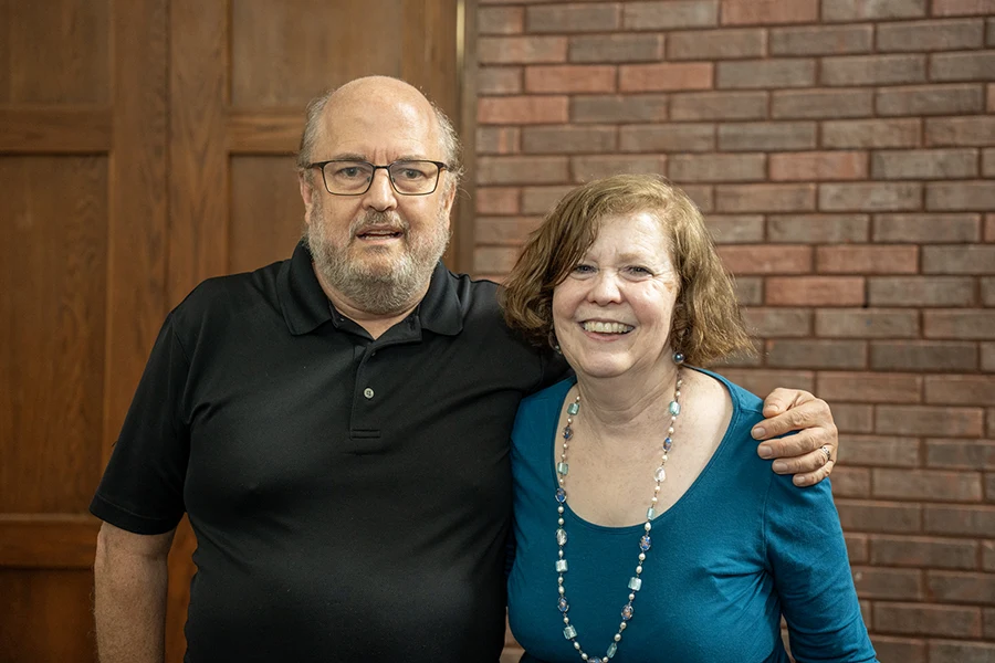 Duane Oldfield and Karen Kampwirth ’86 link arms and smile at the camera.