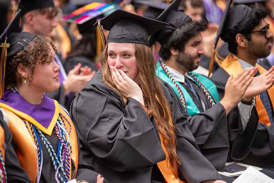 Graduating students sit in a crowd outside.
