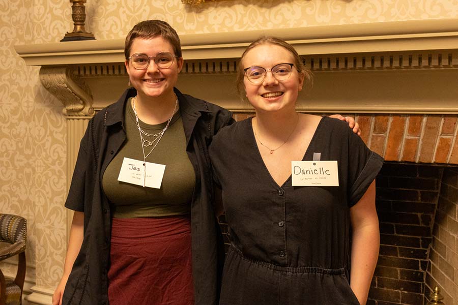 Two students dressed in professional wear stand next to each other and smile for the photo