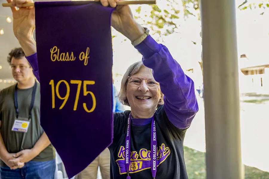 A woman holds a purple Class of 1975 banner.