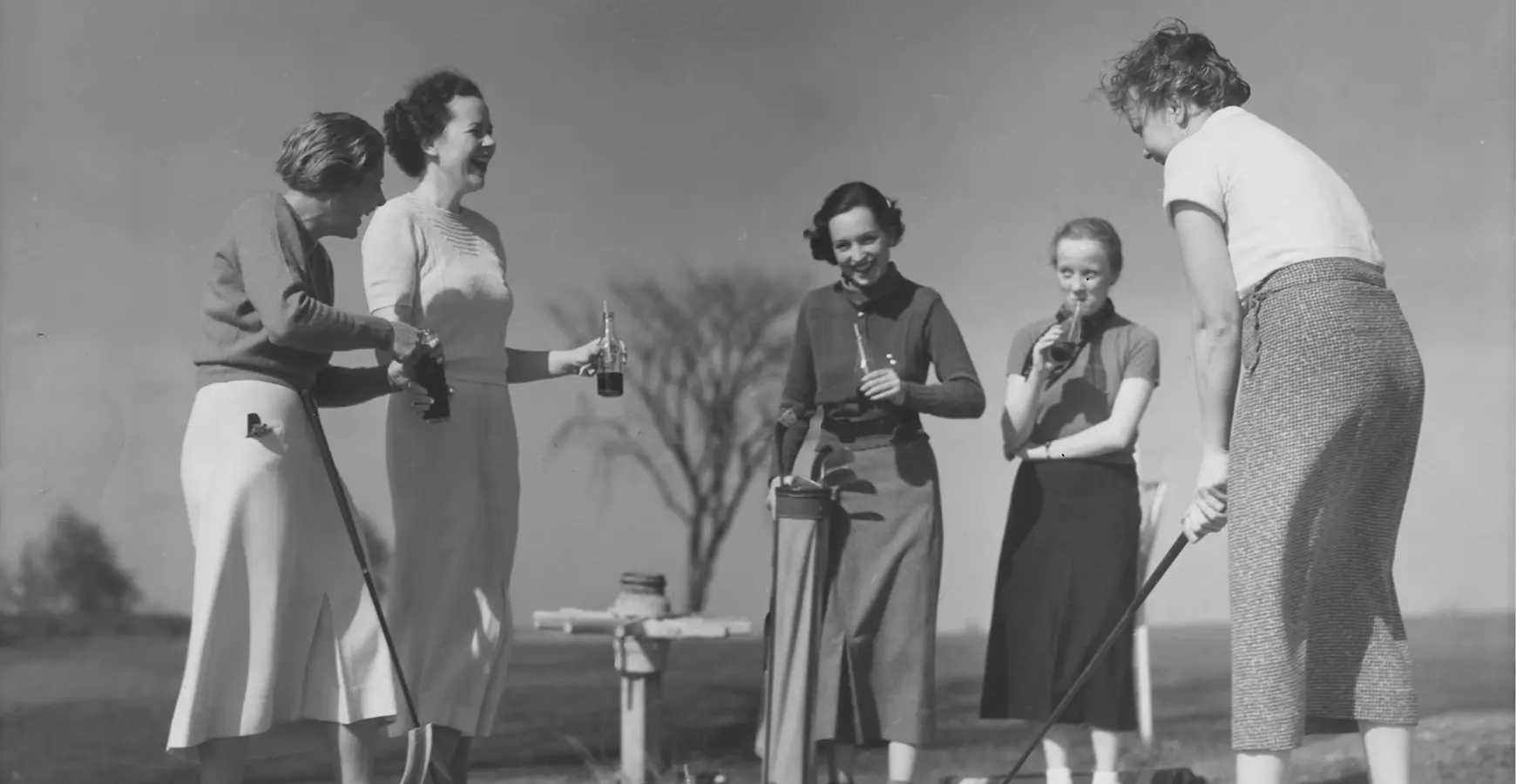 A black and white photo of the Knox women's golf team, circa 1950. Four students watch as one students takes a putt. 