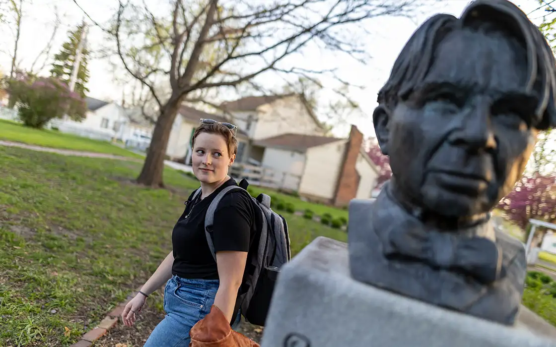 A Knox students sits next to a statue of poet Carl Sandburg, native of Galesburg.