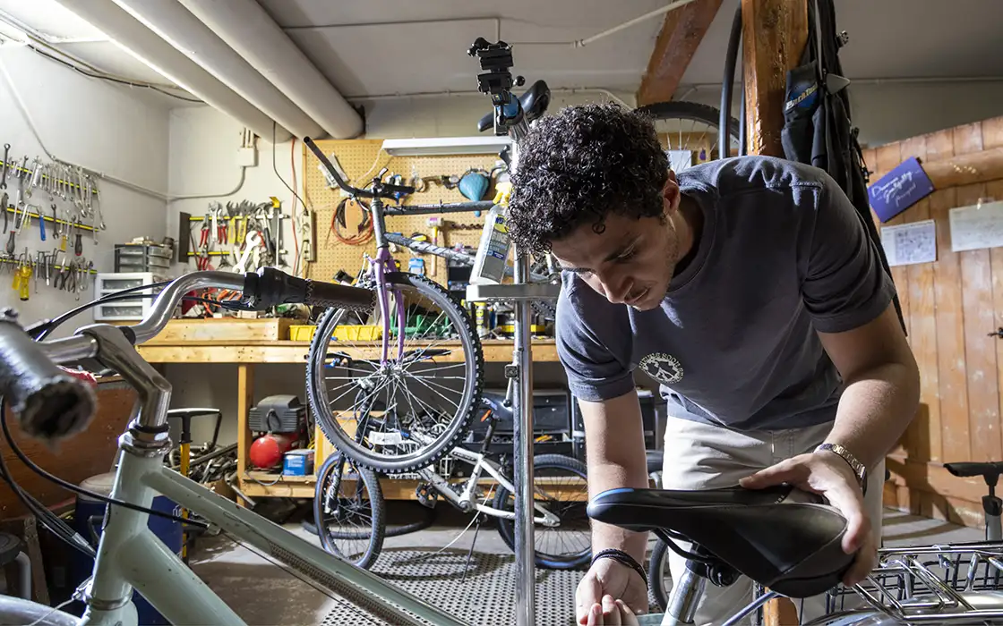 A student works on attaching the seat to a bicycle in the Knox College on-campus bike shop.