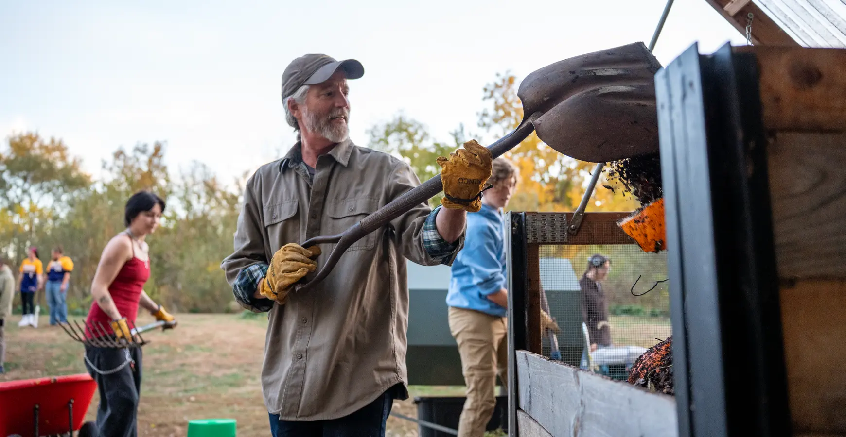 William Hope drops a scoop of material into a bin using a shovel. 