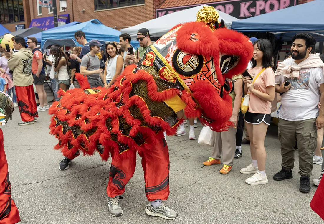 A traditional Chinese dragon puppet dances in the street, surrounded by onlookers.