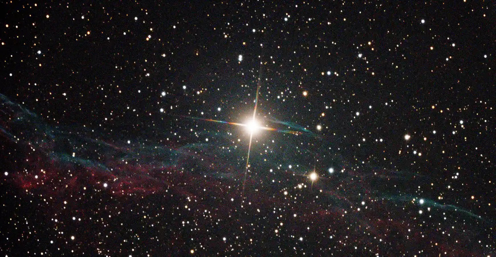 Image taken through a telescope. Stars are visible with one large, bright star in the center.