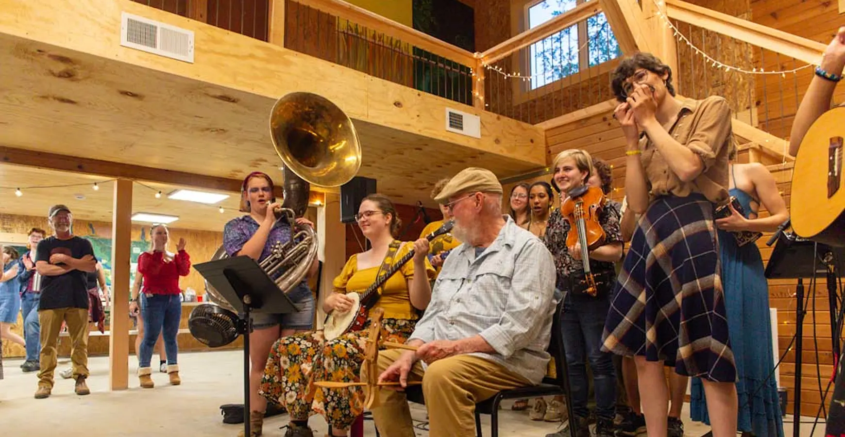 Beneath a balcony, a band plays music as people in the background clap along and enjoy the sounds.
