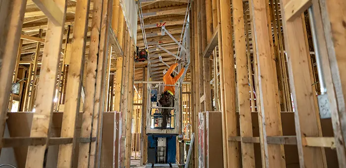 A construction worker stands in the middle of a series of wooden wall frames during construction of the Knight Living & Learning Center at Green Oaks.