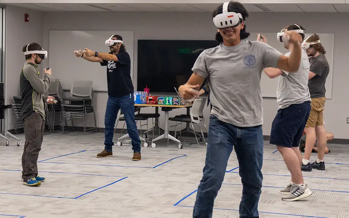 A group of four students wear occuli; each are playing a VR game.