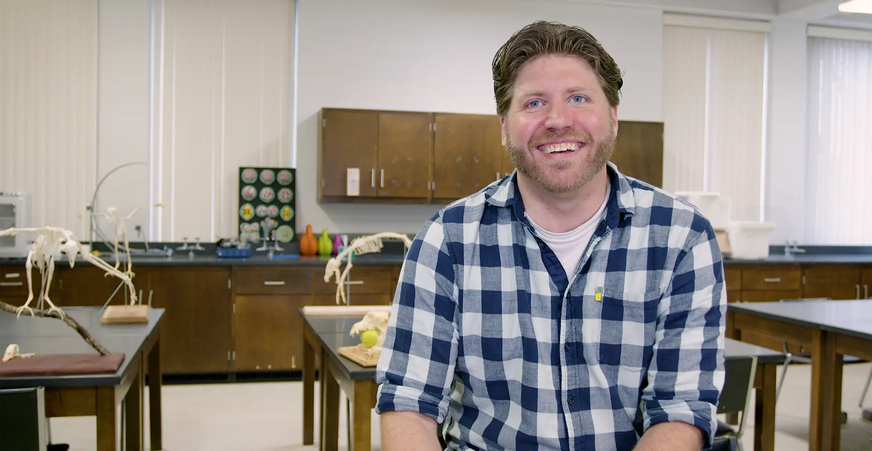Professor Nick Gidmark smiles at the camera in a lab environment. Animal skeletons are visible in the background.