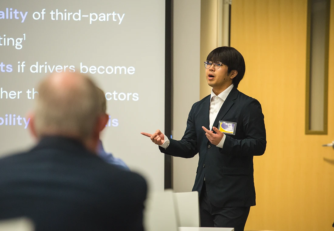 Dressed in a suit, a student gives a presentation to his business class.