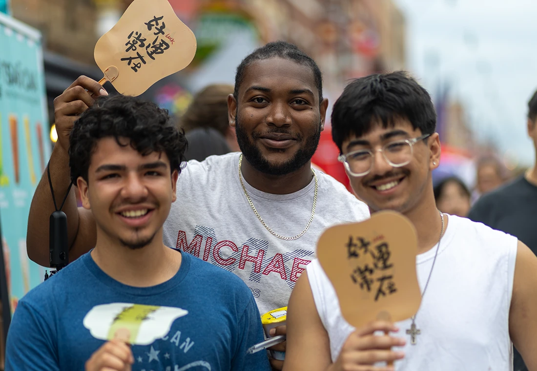 Three students hold up small signs with CJK characters on them.