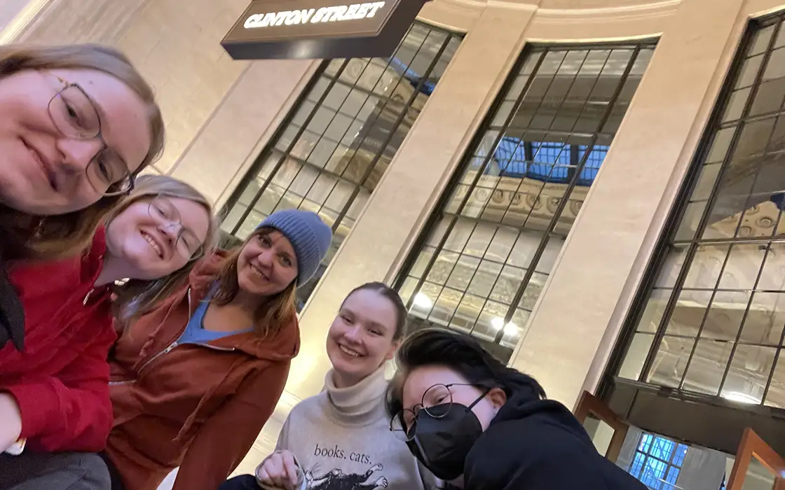 A group of students and Professor Hilary Lehmann smile for a selfie in Union Station.