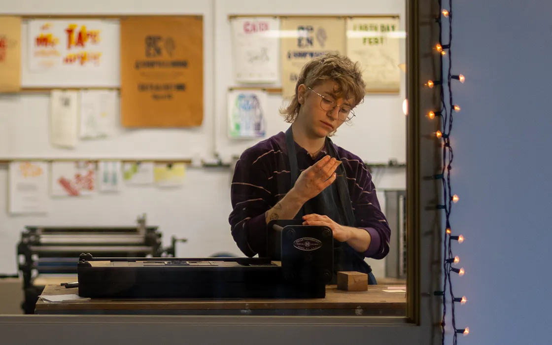 A student stands in front of a letterpress at Knox College.