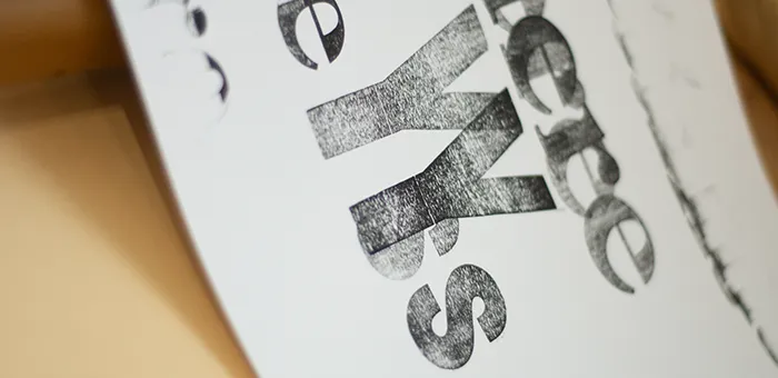 A proof of a white card with large black type that was printed on a leterpress.