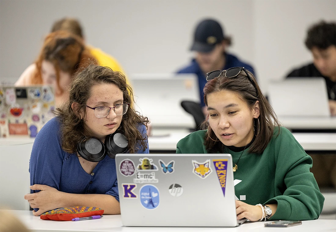 Two students work together on a laptop.