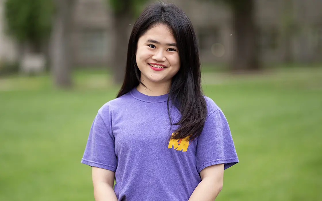 Seeun Tina Jeon smiles at the camera, wearing a purple shirt. A green lawn serves as her backdrop. 
