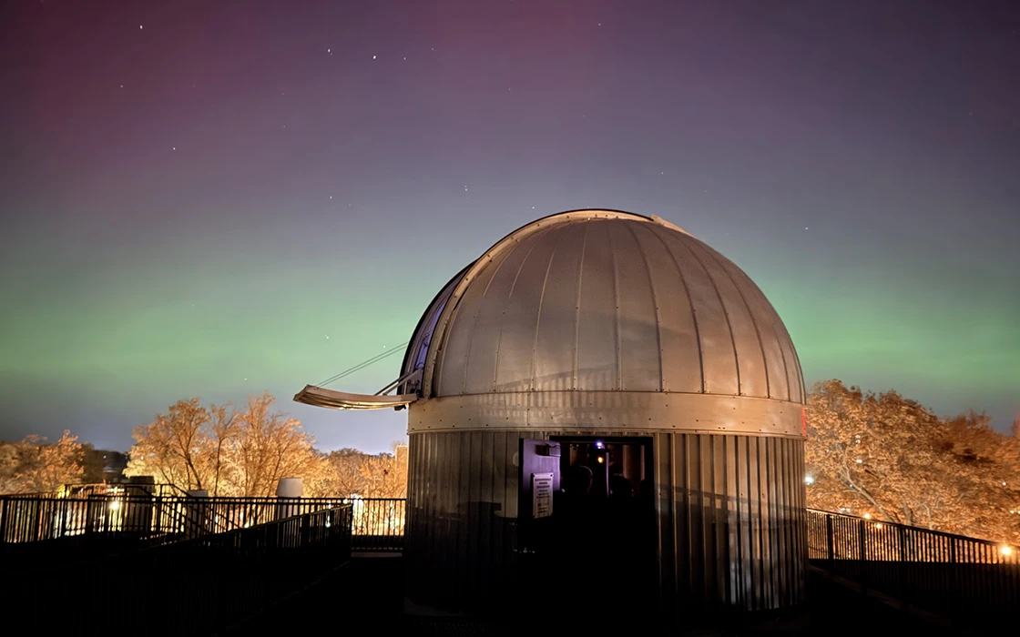 Knox's rooftop observatory is visible against a colorful, Northern light-like sky.