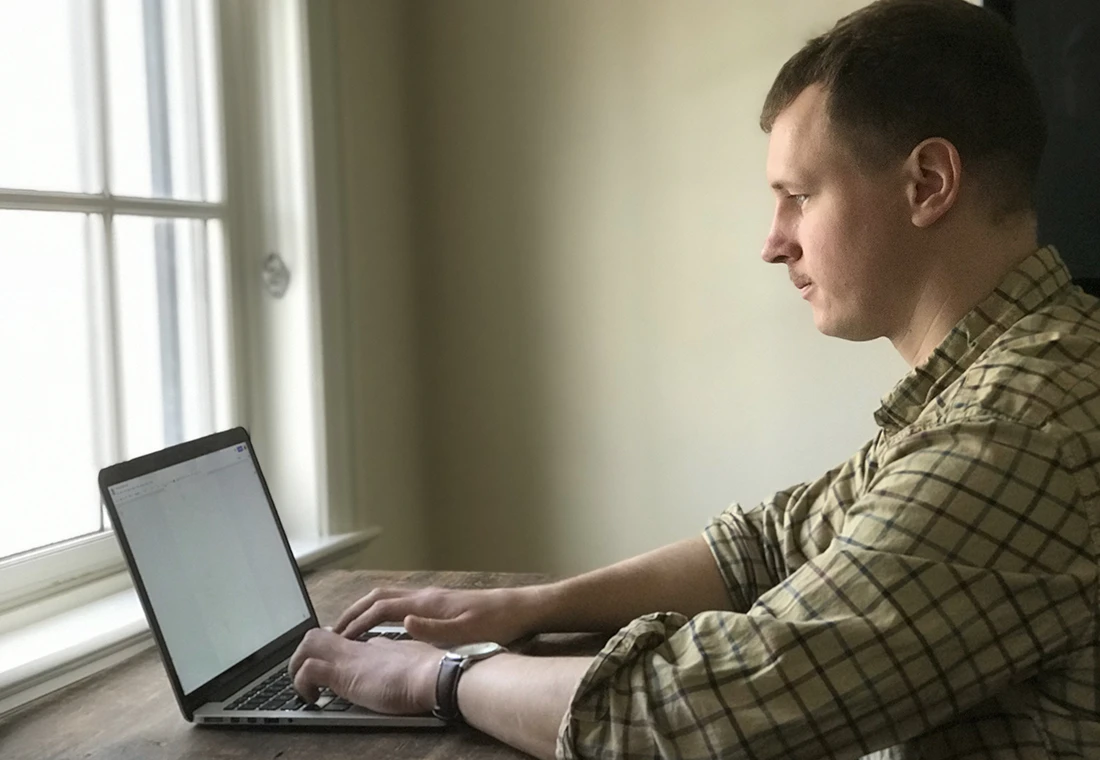 Profile image of a student working on a laptop, facing a window. 