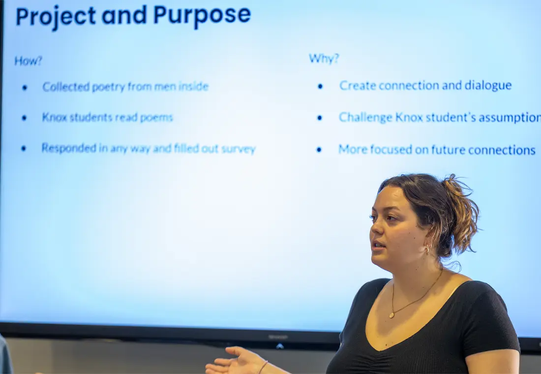 A woman stands in front of a screen, giving a presentation. Text on the screen suggests an experiment where Knox students were given poetry to read and then surveyed. 