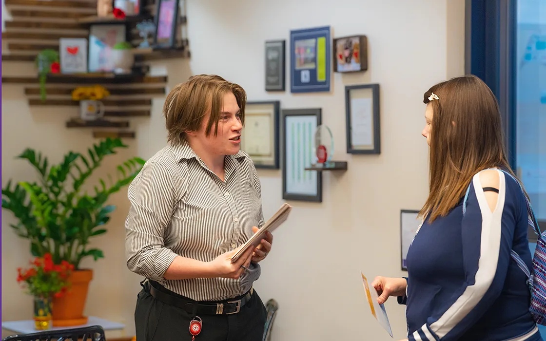 Cianja Bone holds papers, engaged in conversation with an individual.