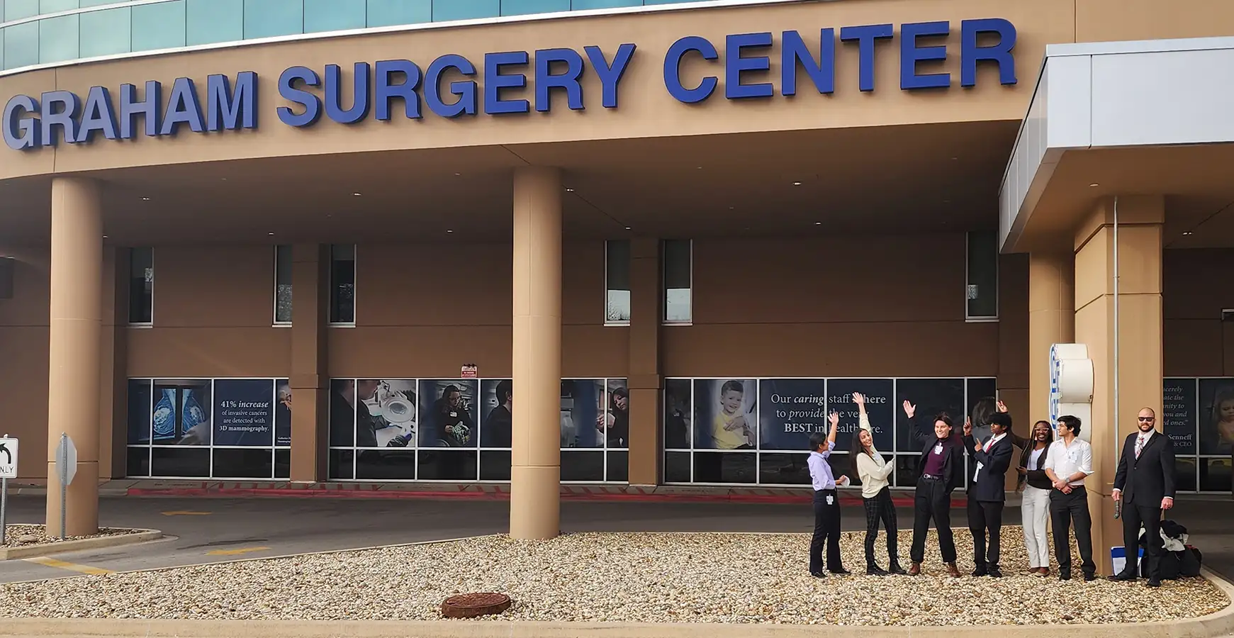 A group of students stand in front of a sign that says Graham Surgical Center.
